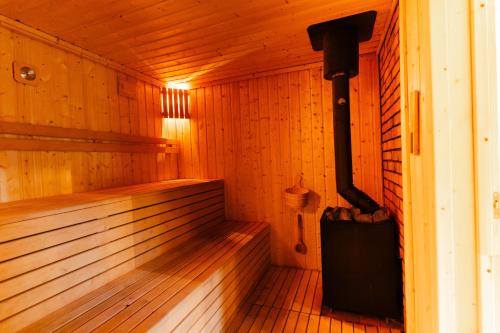 an empty wooden sauna with a black boiler and a suitcase at Flora & Sauna Kamieńczyk Konwaliowa 8 in Błonie