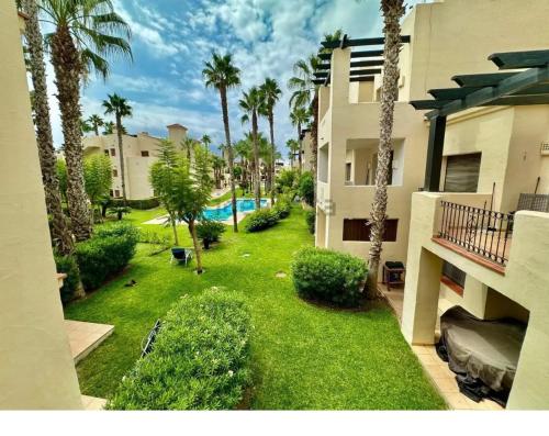 une cour avec des palmiers et une piscine dans l'établissement La Cabaña Roda Golf Sol, à Roda