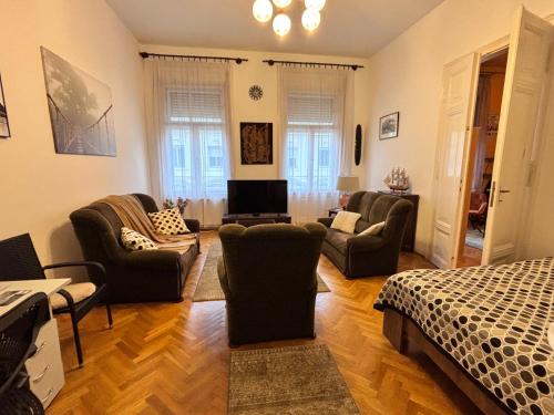 ein Wohnzimmer mit Sofas, Stühlen und einem Bett in der Unterkunft Wagner Apartman in Szeged