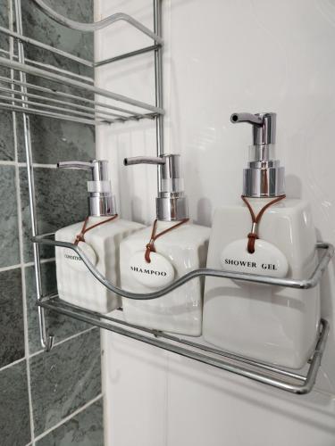 a bathroom with three soap dispensers on a shelf at Baan Fah Chiangrai in Chiang Rai
