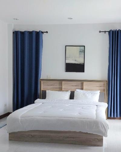 a bedroom with a large bed with blue curtains at Baan Fah Chiangrai in Chiang Rai