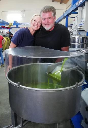 a man and a woman standing behind a pot of food at La Bella Vita Agriturismo in Chiaramonte Gulfi