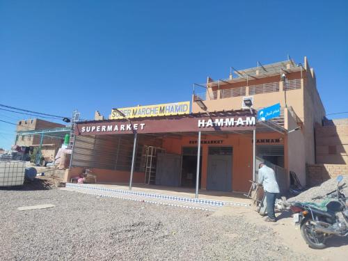 a man standing in front of a building at Hôtel super marché in Mhamid