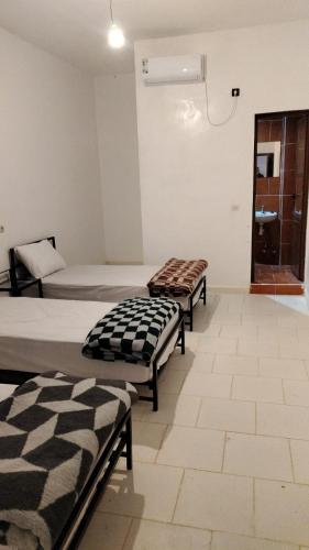 two beds in a room with at Hôtel super marché in Mhamid