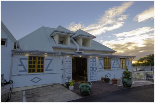 a white house with yellow windows and a sunset at La Fournaise Hotel Restaurant in Sainte-Rose