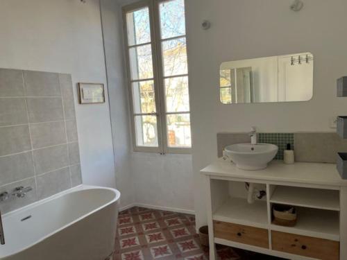 une salle de bain blanche avec une baignoire et un lavabo dans l'établissement L'Ostal de Terralha avec piscine au centre du village, à Montfrin