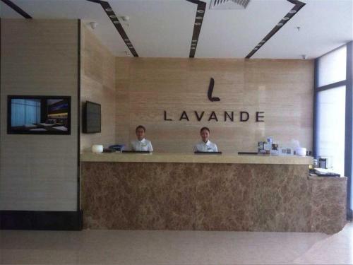 two people sitting at a counter in a lobby at Lavande Hotel Beijing Tongzhou Guoyuan in Tongzhou