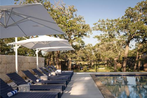 a row of lounge chairs with umbrellas next to a pool at ParcBlu in Fredericksburg