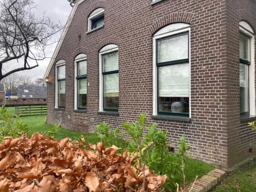 a brick house with windows and a pile of leaves at De kop van Drenthe voorhuis in Vries