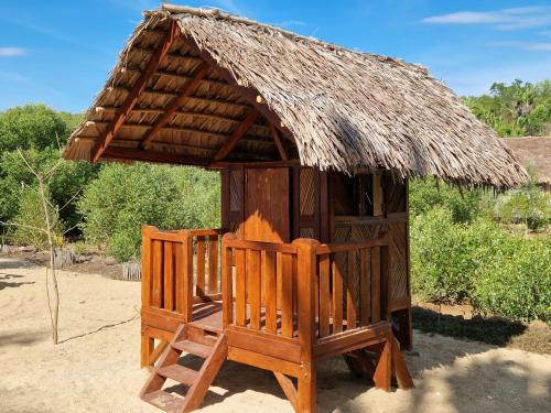 a small hut with two chairs and a thatch roof at Long Beach Resort, Nosy Be in Nosy Be