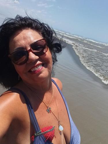 a woman wearing sunglasses standing on the beach at CANTO DO PARAÍSO Praia RUÍNAS in Peruíbe