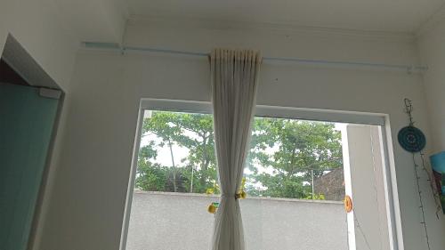 a window with a curtain in a room at CANTO DO PARAÍSO Praia RUÍNAS in Peruíbe