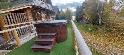 a wooden house with a trash can on the grass at Chata Nad Jeziorem Czorsztyńskim -Jaquzzi zewnętrzne in Maniowy