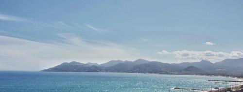 une grande étendue d'eau avec des montagnes en arrière-plan dans l'établissement Cannes 3P Appt 3P Front de Mer Terrasse Piscine VUE MER, à Cannes