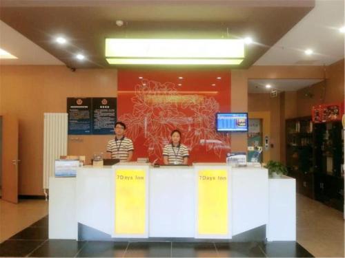 two people standing at a counter in a store at 7Days Premium Beijing Wangjing Nanhu Dongyuan in Beijing
