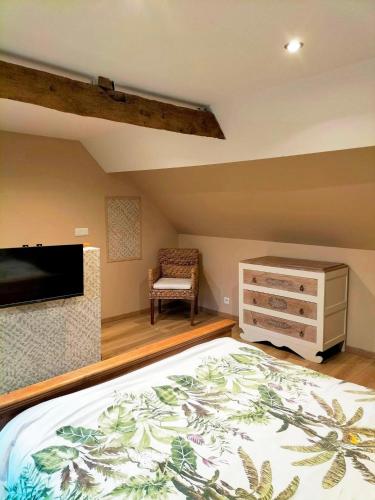 - une chambre avec un lit, une commode et une télévision dans l'établissement Les Chambres de Saint Hilaire, à Saint-Hilaire-Cottes