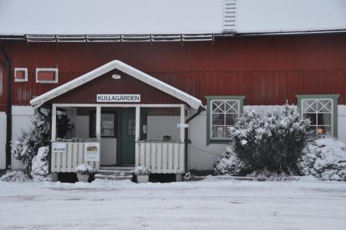 a red barn with a building with snow on it at Kullagården in Vreta Kloster