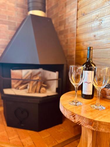 a bottle of wine sitting on a table with two glasses at Cabanas Recanto das Lagoas in Bom Retiro