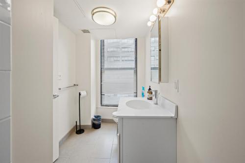 a white bathroom with a sink and a window at Furnished Apartment in Downtown in Boston