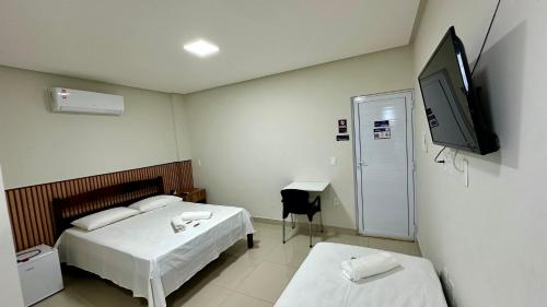 a bedroom with two beds and a tv on the wall at Hotel Brisas in Bom Jesus da Lapa