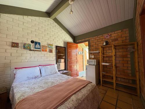 um quarto com uma cama e uma cozinha com geladeira em Suíte Rústica em Florianópolis