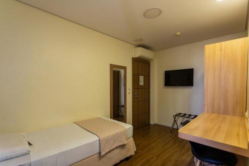 a hotel room with a bed and a television at Hotel Amália in Sao Paulo
