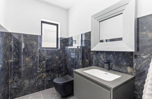 a bathroom with a sink and a toilet and a mirror at Modern Mile 16 Beach Estate Home in Yzerfontein