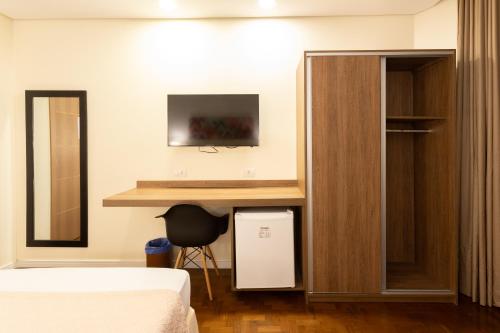 a room with a bed and a desk in a room at Hotel Amália in Sao Paulo