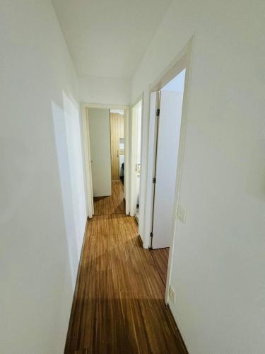 an empty hallway with white walls and wood floors at Aeroporto de Guarulhos 3 in Guarulhos