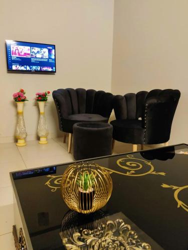 a living room with chairs and a table and a television at Private & Cozy 2-Bedroom Full Apartment for Families E11 Islamabad in Islamabad