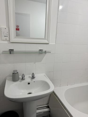 a bathroom with a sink and a mirror and a tub at Livingwell apartments in Chatham