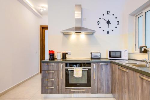 a kitchen with a counter and a clock on the wall at Amazing Location in St Julian's, Paceville 2 Bedroom, with Balcony by Vaganza in St Julian's
