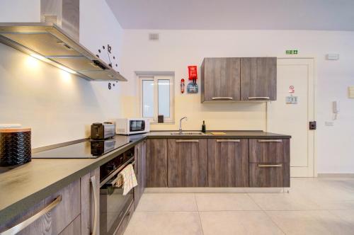 a large kitchen with wooden cabinets and a sink at Amazing Location in St Julian's, Paceville 2 Bedroom, with Balcony by Vaganza in St Julian's