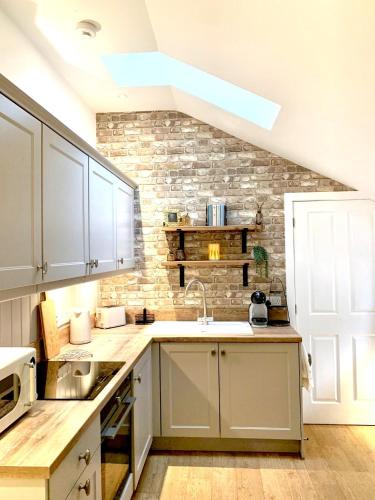 a kitchen with white cabinets and a brick wall at Quaint Cottage in Kirkwall in Kirkwall