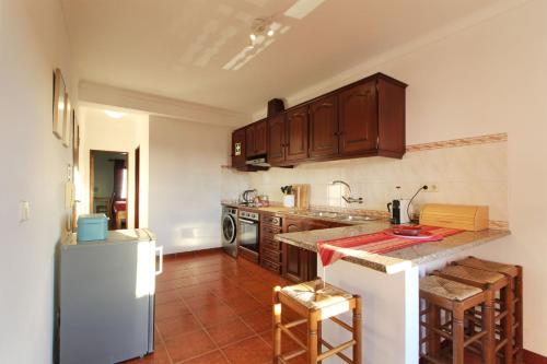 Una cocina con gabinetes de madera y encimera. en Casa Papoila T1 com terraço, en Vila Nova de Milfontes