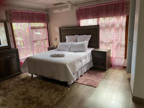a bedroom with a large bed and two windows at Peaceful picturesque Pecanwood in Hartbeespoort
