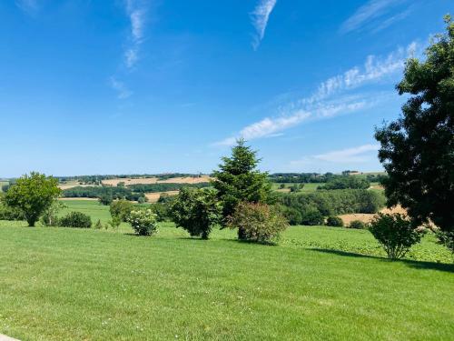 un champ d'herbe verte avec des arbres au loin dans l'établissement NOUVEAUTE Maison avec vue dominante sur la campagne, à Lamontjoie