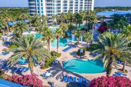 an aerial view of a resort pool with palm trees and chairs at 5 Star Resort 2BR 2 BATH King Suite Shuttle Pools Across from Beach 2208 in Destin
