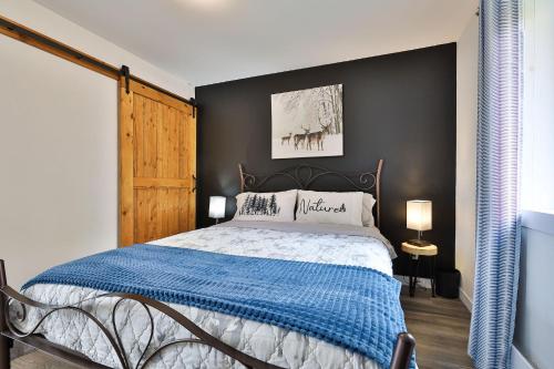 a bedroom with a bed with a blue blanket at Chalet Le Cerf du Lac in Disraeli