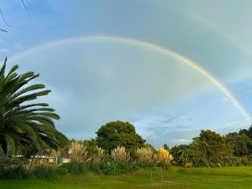 a rainbow in the sky over a park at Hotel Rancho Las Margaritas in Valle de Bravo