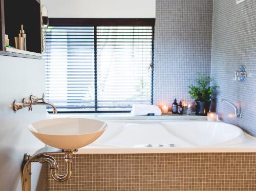 a bathroom with a bath tub and a sink at Empire Spa Retreat in Dunsborough