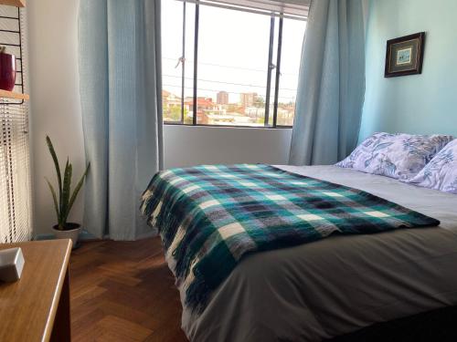 a bedroom with a bed with a plaid blanket on it at CasaOcho in Viña del Mar
