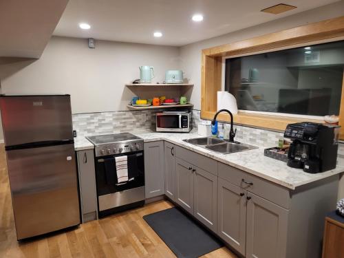 a kitchen with a stainless steel refrigerator and a sink at The Suite Treat in Whitehorse