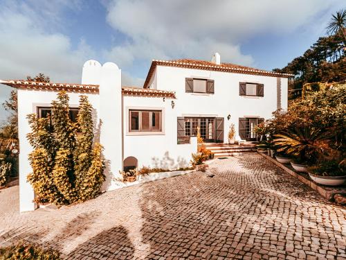 a white house with a cobblestone driveway at Oliveira's House By Gt House in Sintra