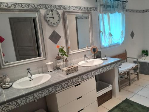 La salle de bains est pourvue de 2 lavabos et d'une horloge murale. dans l'établissement La Bartavelle, à Eyragues