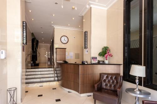 a lobby with a chair and a clock on the wall at Hotel Amália in Sao Paulo