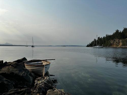 a small boat sitting on the shore of a lake at Thetis Island Get Away Cottage in North Galiano