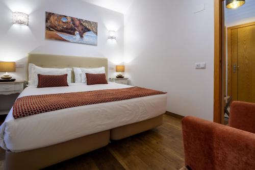 a bedroom with a large bed and two chairs at Monte das Perdizes in Olhão