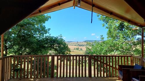 a wooden deck with a view of a field at Glamping Podere Angiotto LODGE QUERCIA in Magliano in Toscana