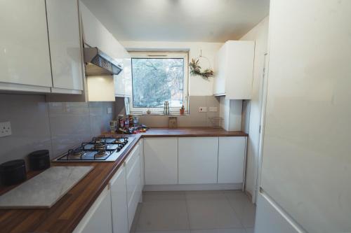 a small kitchen with white cabinets and a window at 1 Bed-Park View-Balcony-WiFi-Pet Friendly in London